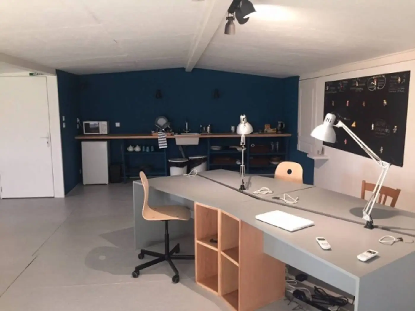 Les postes de travail en openspace : tables longues, assises et lampes de bureau.
