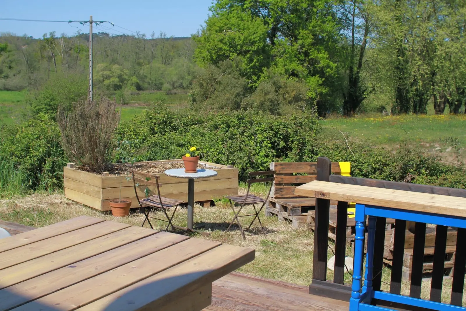 Le jardin de Kontainer : bacs en bois, table de bistrot et verdure des Landes derrière la rambarde.