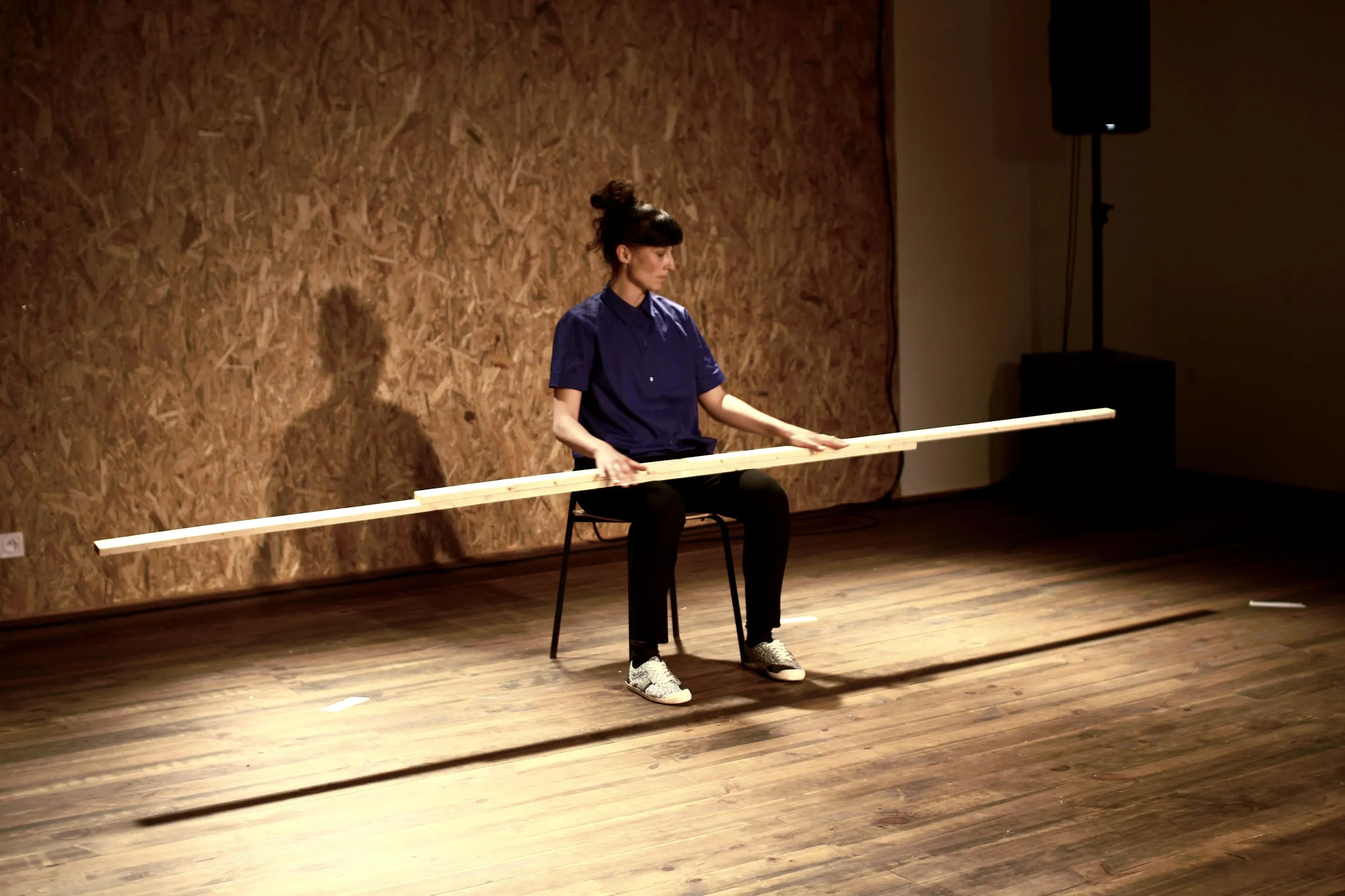 Danseuse assise tenant un long bâton de bois